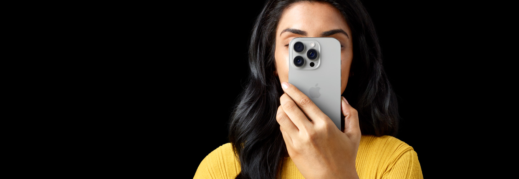 A person holding an iPhone 16 Pro, blocking their face.